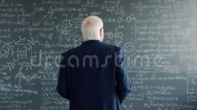 有经验的科学家在大学课堂上走到黑板墙上看公式
